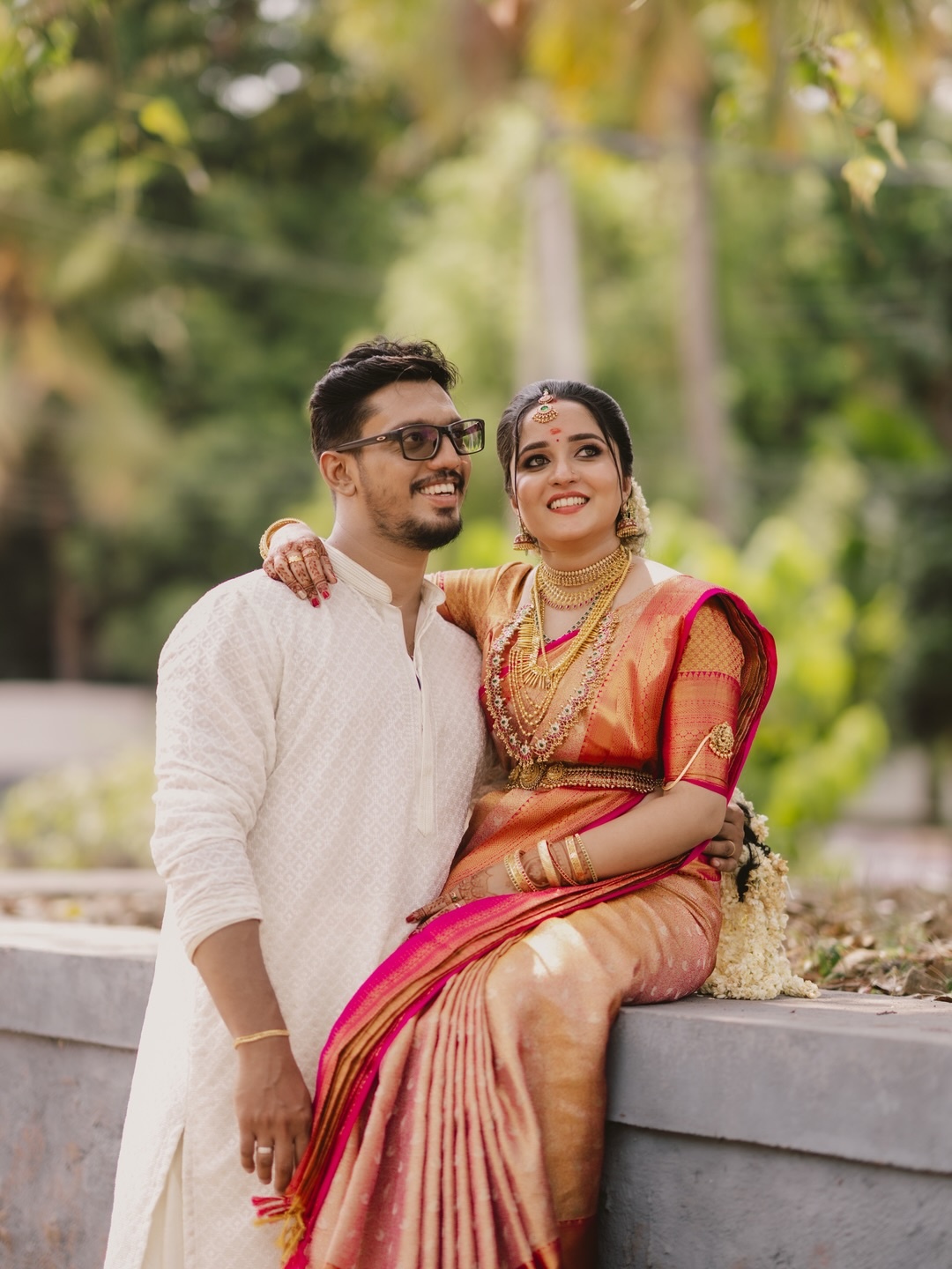 A couple in traditional attire standing beside a clay vessel